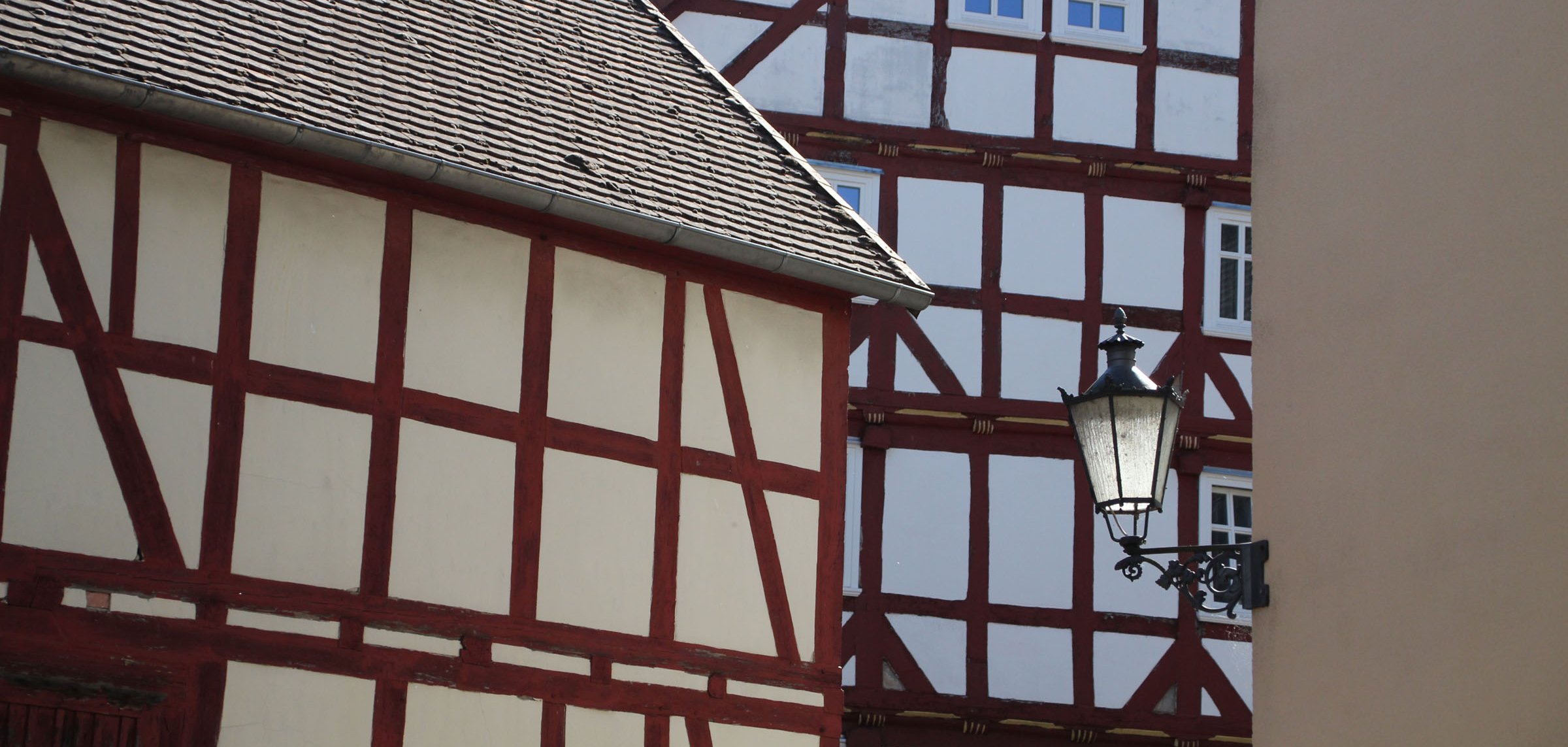 Ansicht mit drei Fachwerkhäusern und einer Straßenlaterne