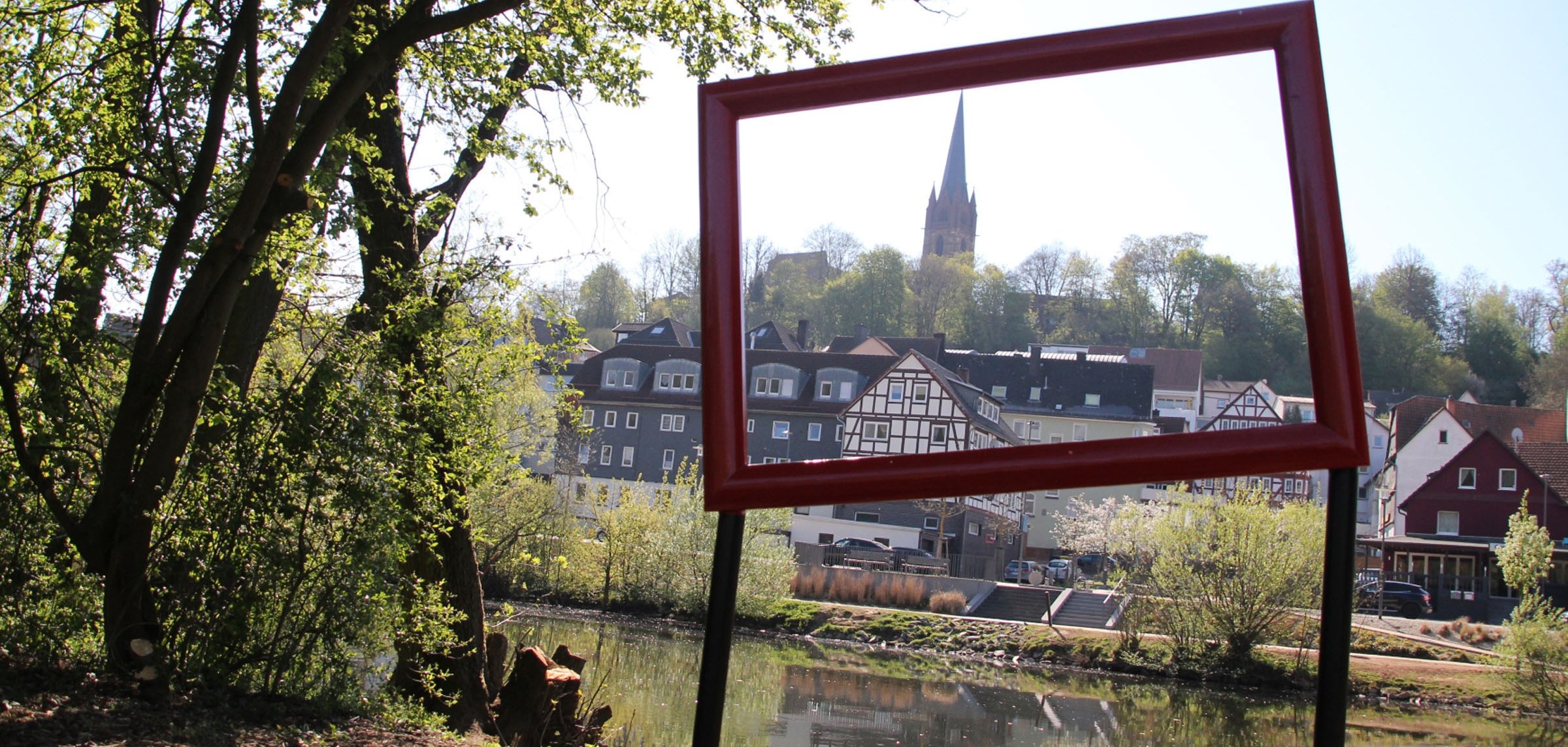 Ein Metallrahmen am Ederufer lädt zum Fotografieren der Stadtansicht ein