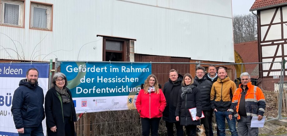 Menschengruppe aufgereiht vor einem abzureißenden Haus