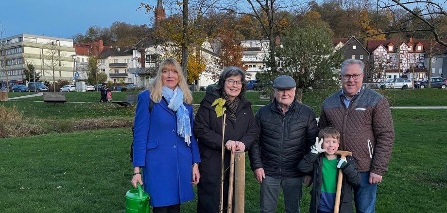Vier Personen mit Spaten und Gieskanne auf einer Grünfläche