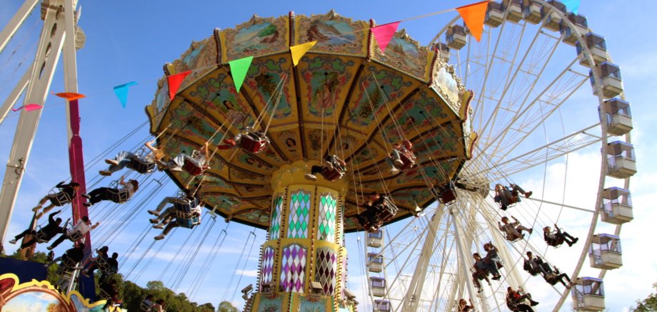 Kirmesszene mit Kettenkarussell und Riesenrad bei schönem Wetter