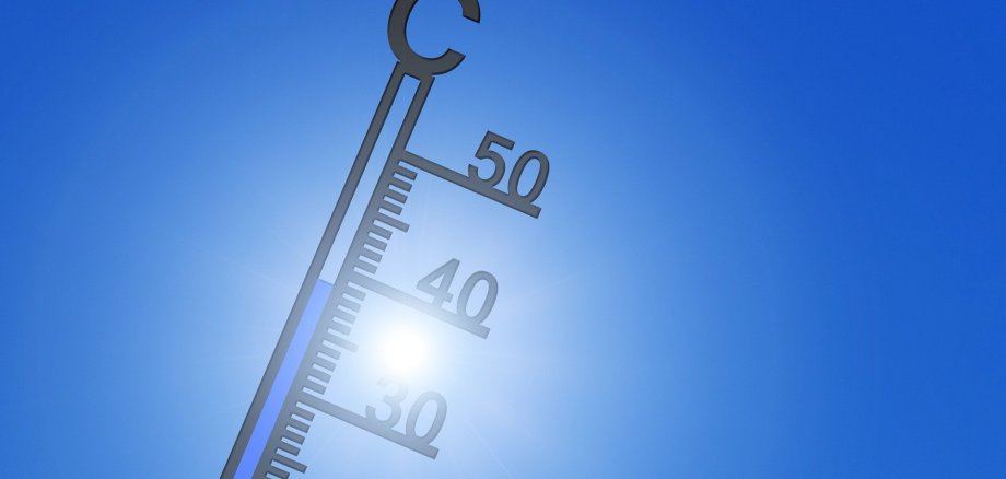 Termometer im Gegenlicht der Sonne vor blauem HImmel
