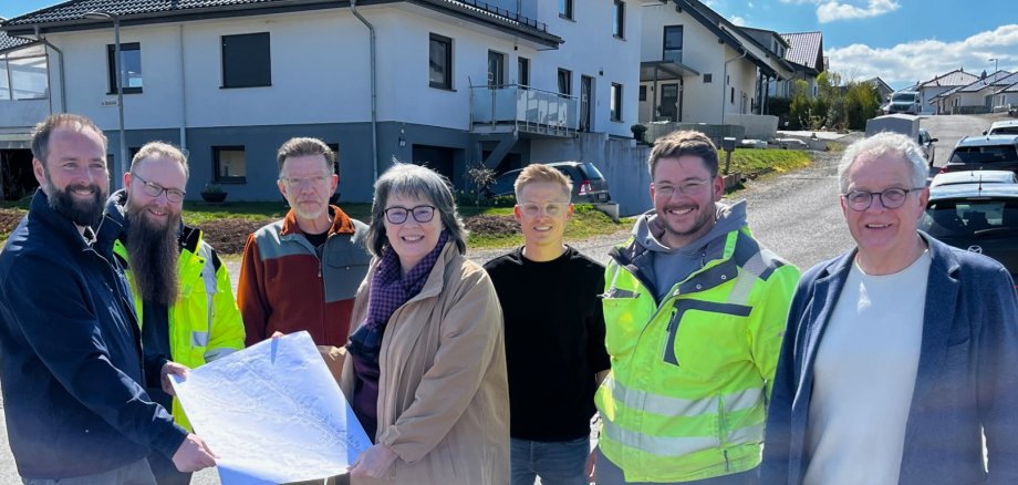 Gruppe von Personen zum Teil mit Sicherheitswesten auf einer Straßenkreuzung vor einem Haus