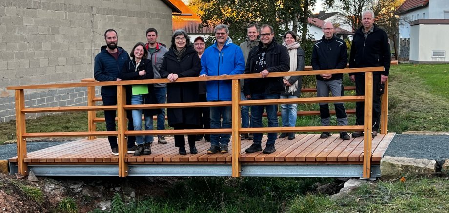 Menschengruppe auf einer kleinen Brücke mit Holzgeländer