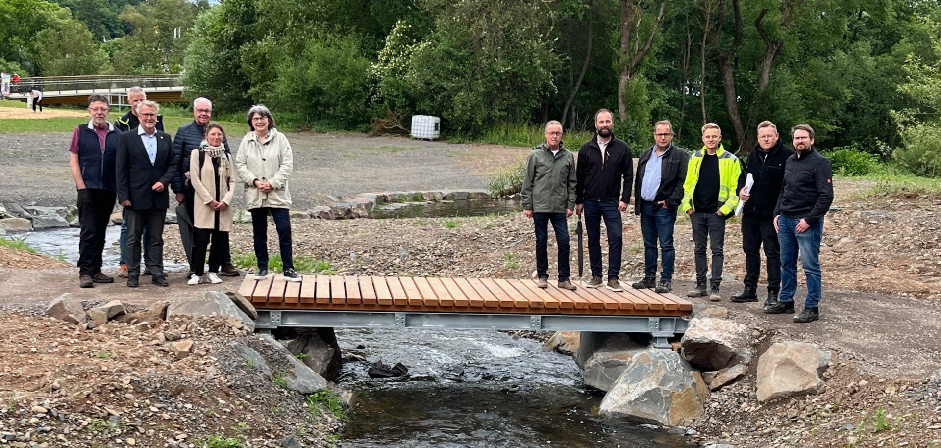 Zwei Personengruppen auf einem kleinen Holzsteg über einen Bachlauf