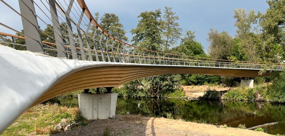 Seitliche Ansicht einer Radverkehrsbrücke aus Holz und Beton