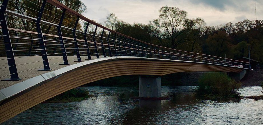 Elegante Holzbrücke über den Fluss Eder bei bewölktem Himmel