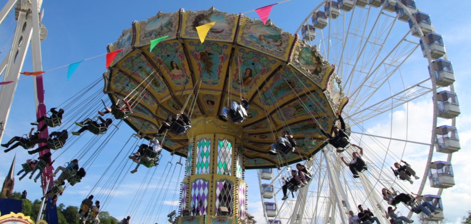 Kettenkarussell und Riesenrad auf einem Jahrmarktgelände bei schönem Wetter
