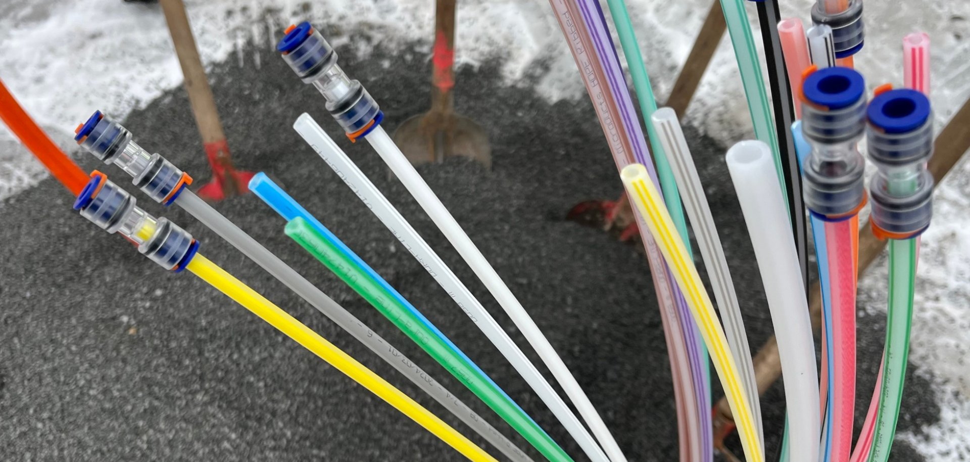 Bunte Glasfaserleitungen die aus einem Kieshaufen herausschauen