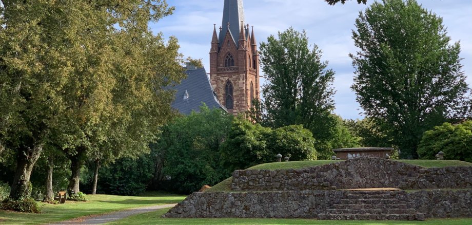 Grünfläche mit historischer Theaterbühne und Kirchturm im Hintergrund