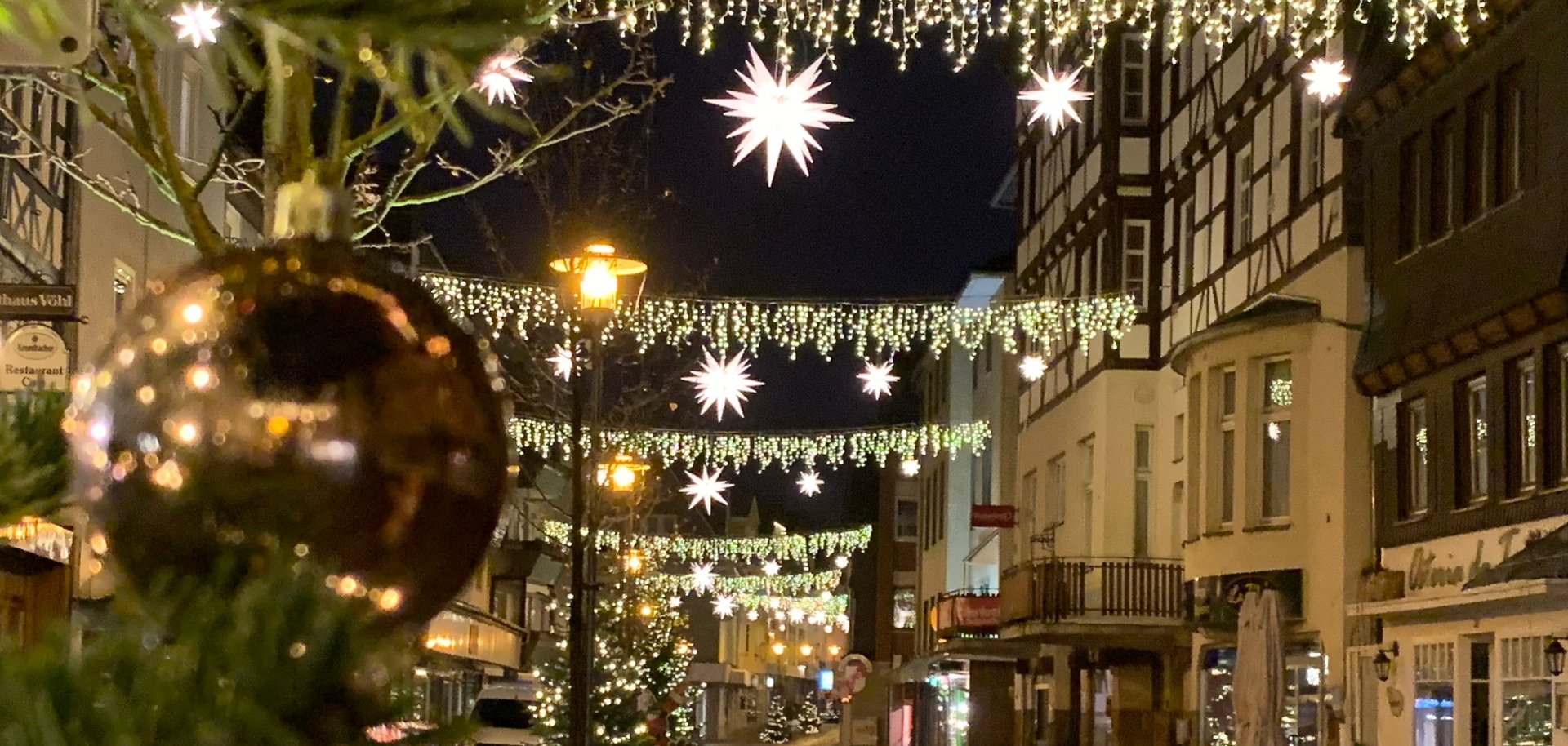 Fußgängerzone mit Lichterketten und Weihnachtsschmuck bei Dunkelheit