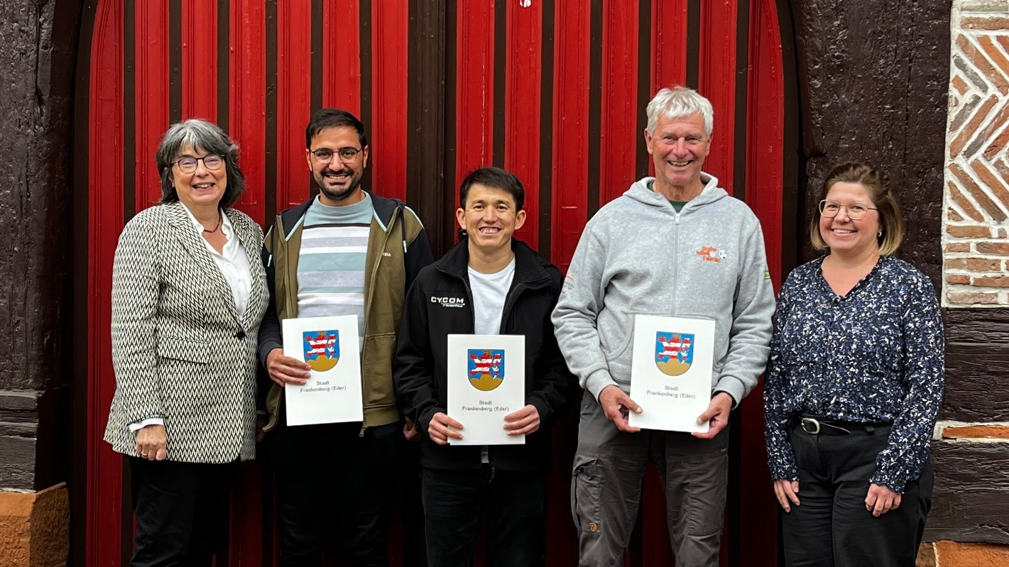 Fünf Personen vor einem roten Holztor