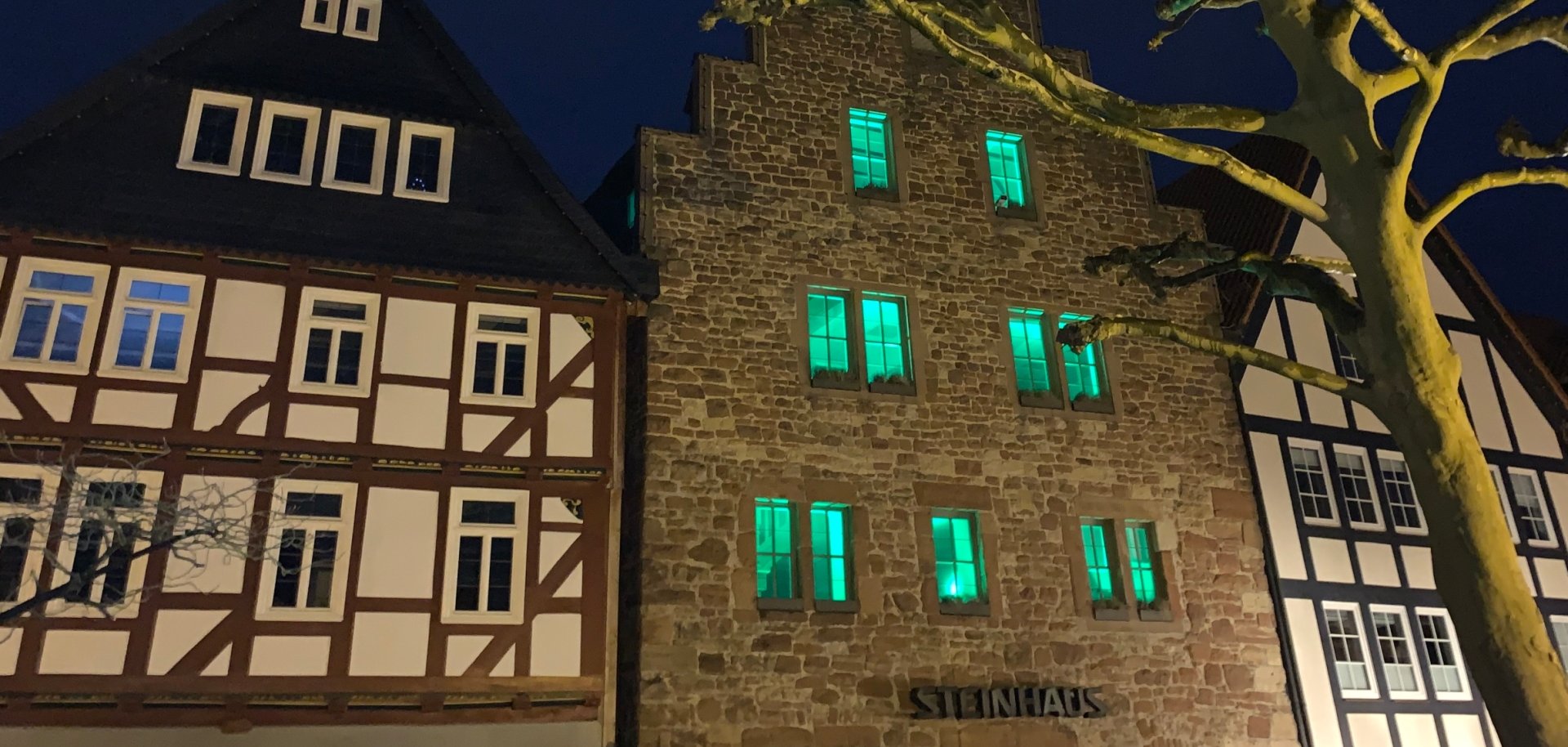 Steinhaus in der Abenddämmerung mit grün erleuchteten Fenstern