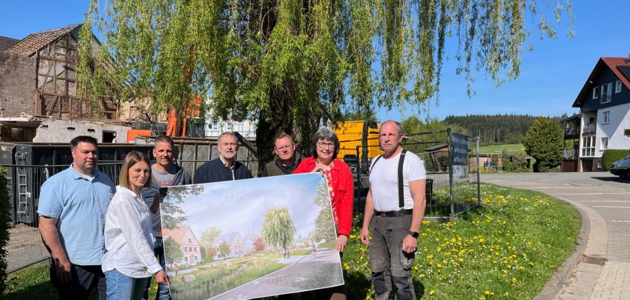 Mehrere Personen mit einem großen Bild vor einem Baum