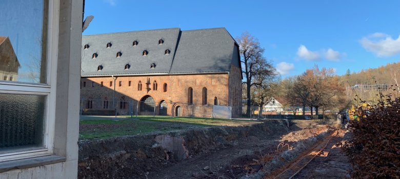 Erdgraben nach Abriss eines Gebäudeteils, im Hintergrund eine historische Klosteranlage