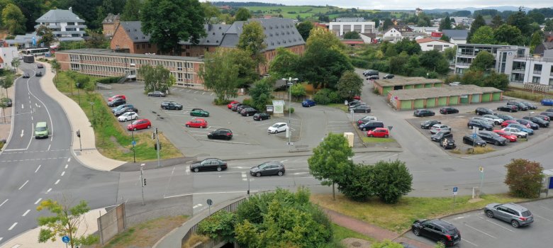 Luftaufnahme mit Kreuzung und Großparkplatz rund um eine Klosteranlage